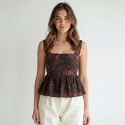 Woman wearing a floral peplum top against a plain background