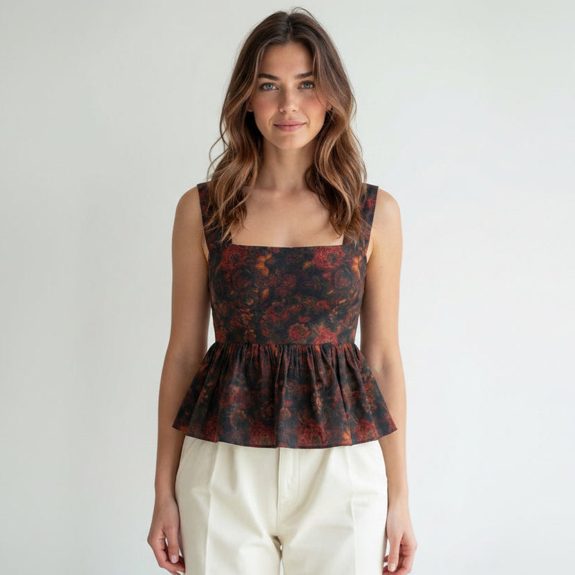 Woman wearing a floral peplum top against a plain background